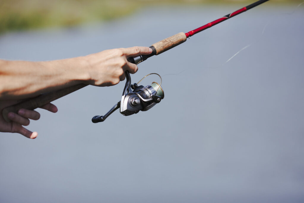 A man fishing with the best spincast reel in hand by the water