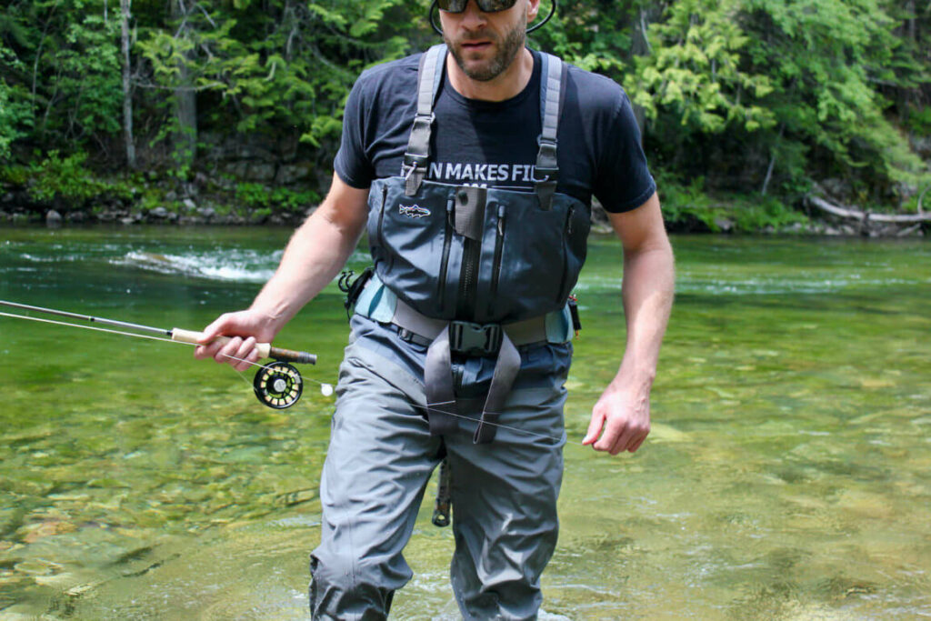 Close-up of waterproof best waders boots in shallow water during a fishing trip