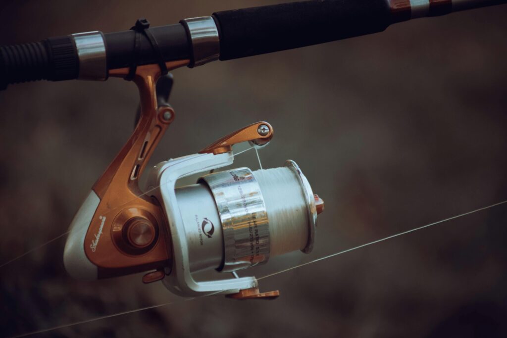 Angler holding a fishing rod equipped with a fishing reel with no anti-reverse trigger