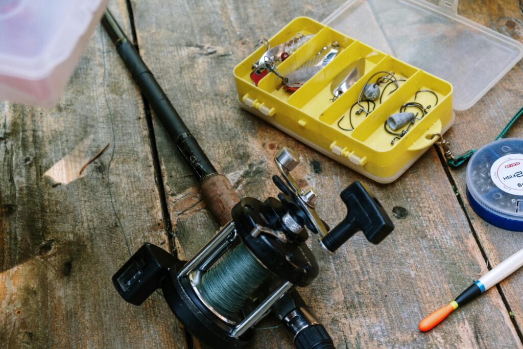 Fishing rod with reel lying on the floor beside a tackle box, ready for setup