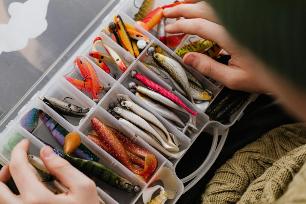 Man holding a fishing tackle box, selecting the best bass fishing lures for bass fishing near the water