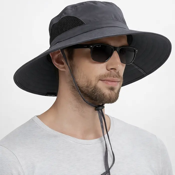 Male model wearing a charcoal gray wide-brim best fishing hat with mesh side panel and chin strap, studio background.